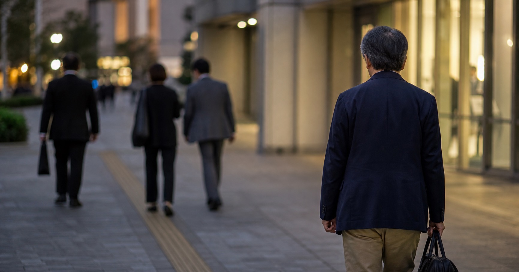 転職後に職場の人間関係の変化を感じながら夕方のオフィス街を歩く50代男性