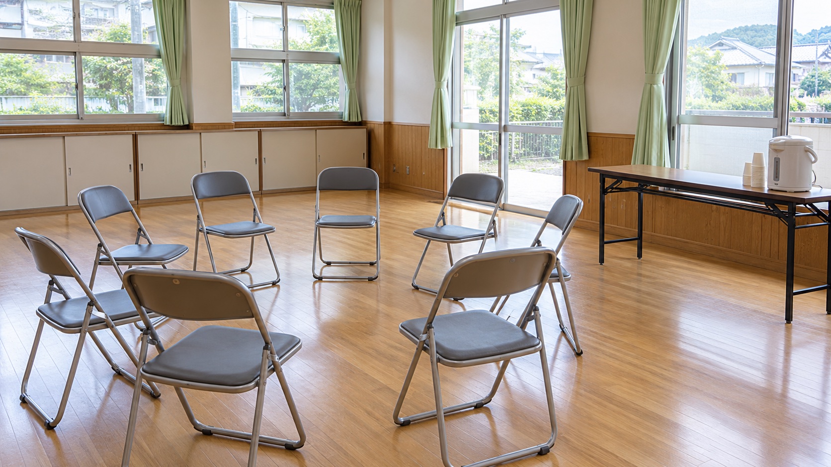 公民館の部屋に輪になって並べられた、誰もいない折りたたみ椅子